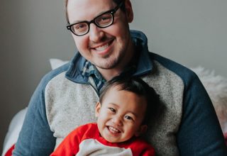 Man with glasses holding smiling baby