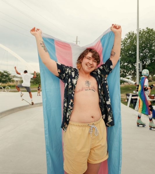 Person holding trans pride flag at skate park