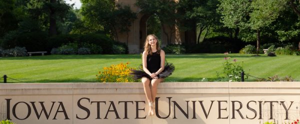 Student seated on Iowa State University sign