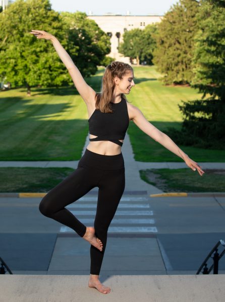 A student strikes a dance pose outside